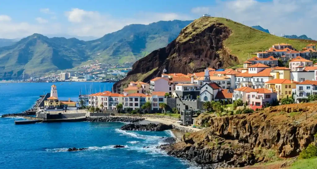 ilha da madeira portugal vista panorâmica do litoral com casas coloridas nas montanhas, oceano azul e vegetação tropical, destino turístico europeu com paisagem natural deslumbrante